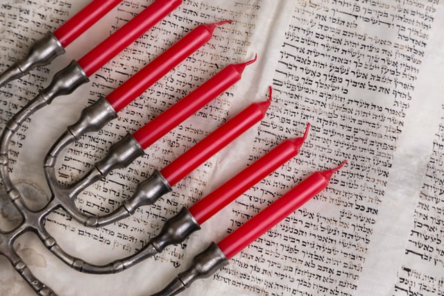 Menorah with red candles placed on Hebrew script