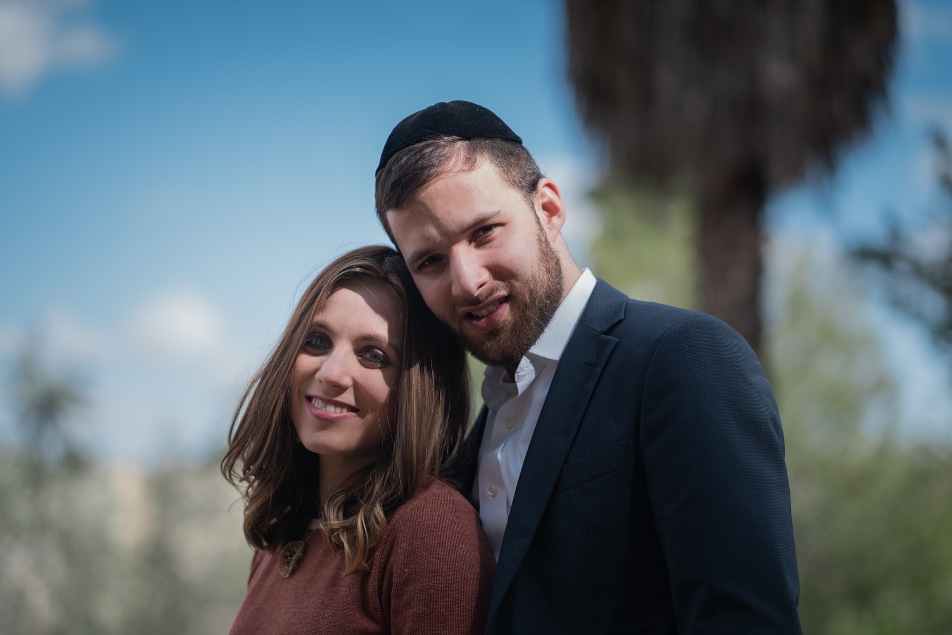 Smiling couple outdoors, with the man wearing a kippah